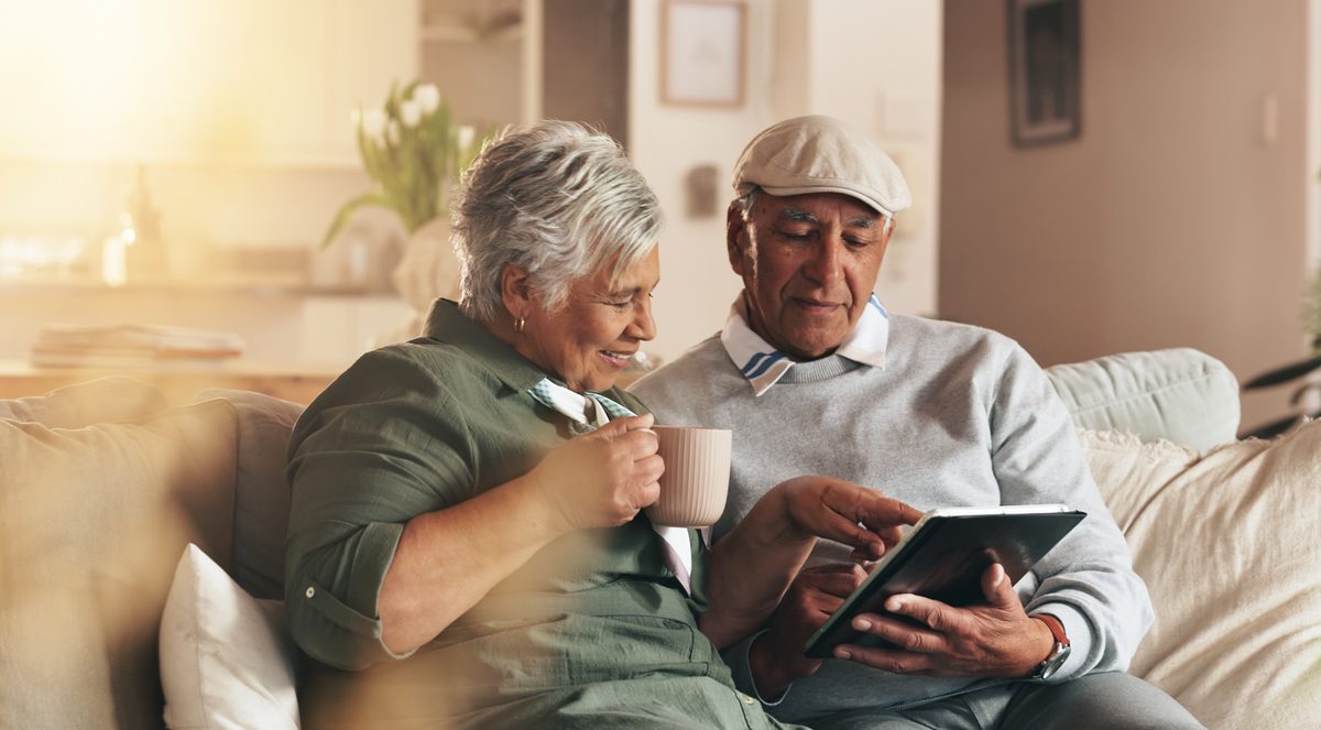 Two people sitting together looking at a tablet at home.