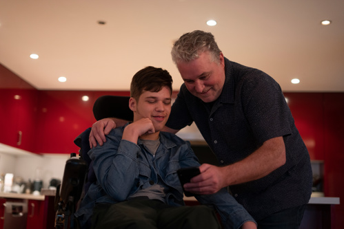 Man showing disabled son information on his phone