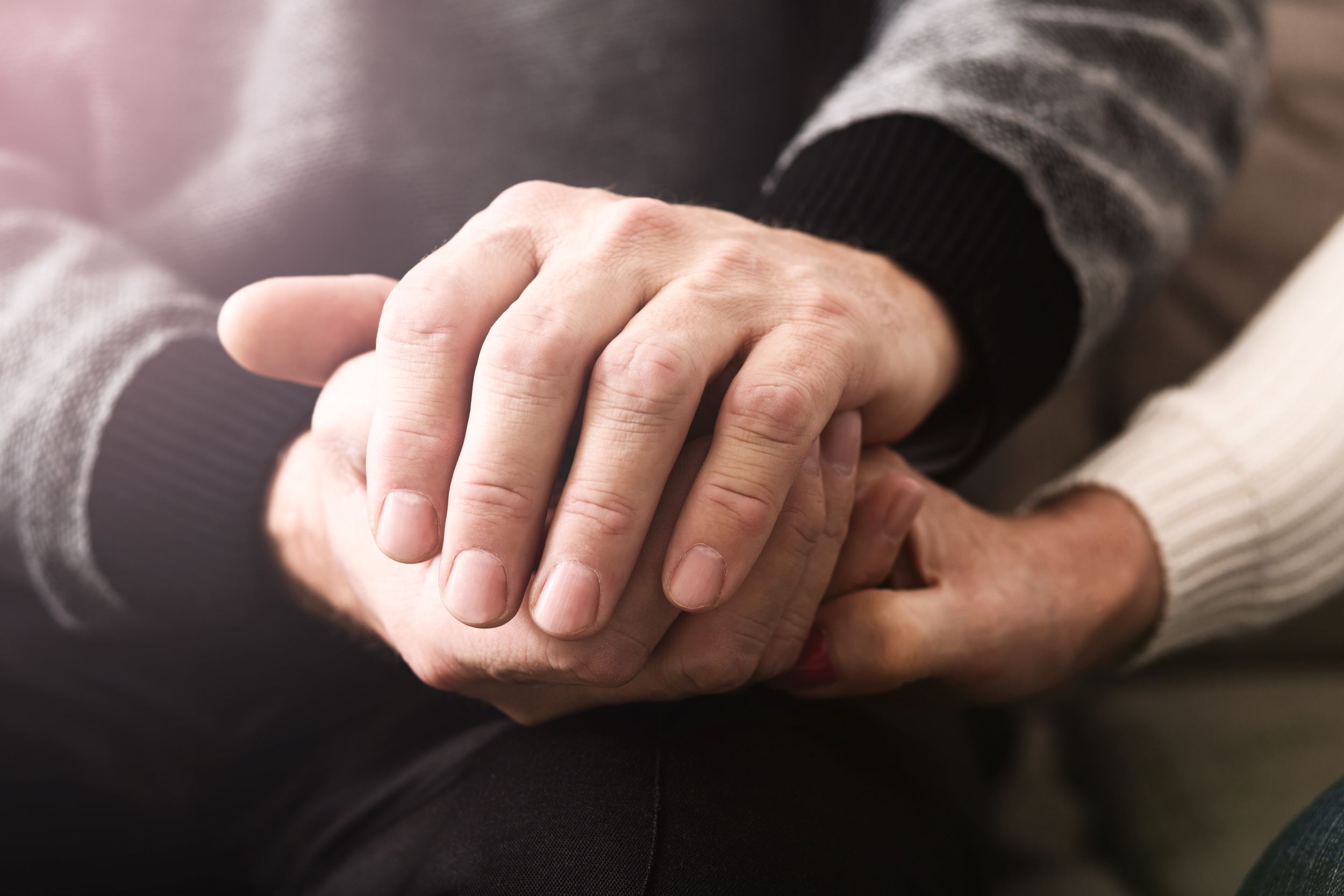 Two pairs of hands holding each other. 