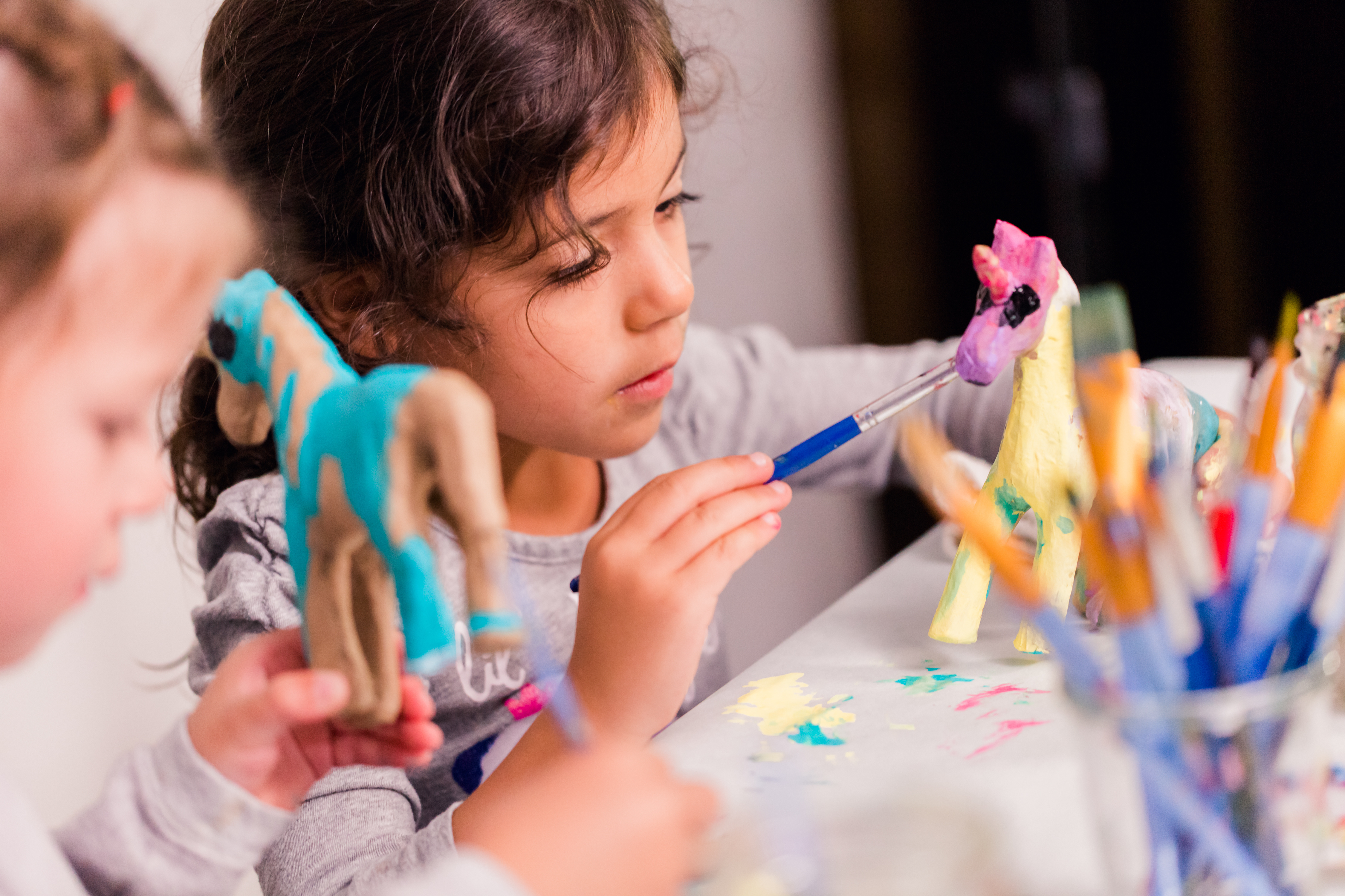 Young girl painting a model horse