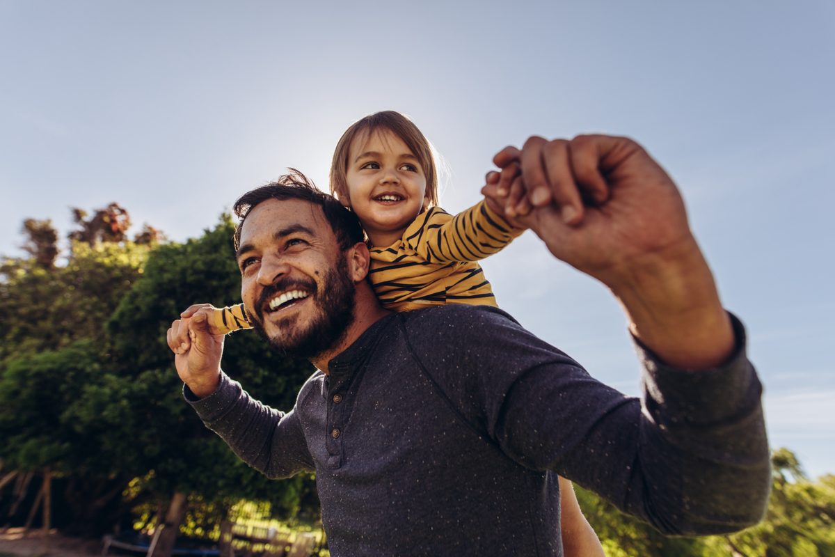 Adult carrying child outdoors.