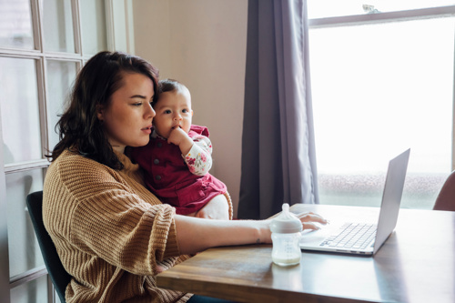 Mum on a laptop holding a baby