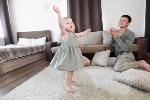 Toddler dancing while dad claps his hands