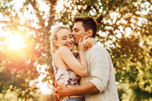Young man kisses young woman on the cheek as they embrace